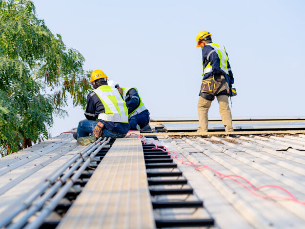 workers installing solar panels, for efficient energy on rooftop